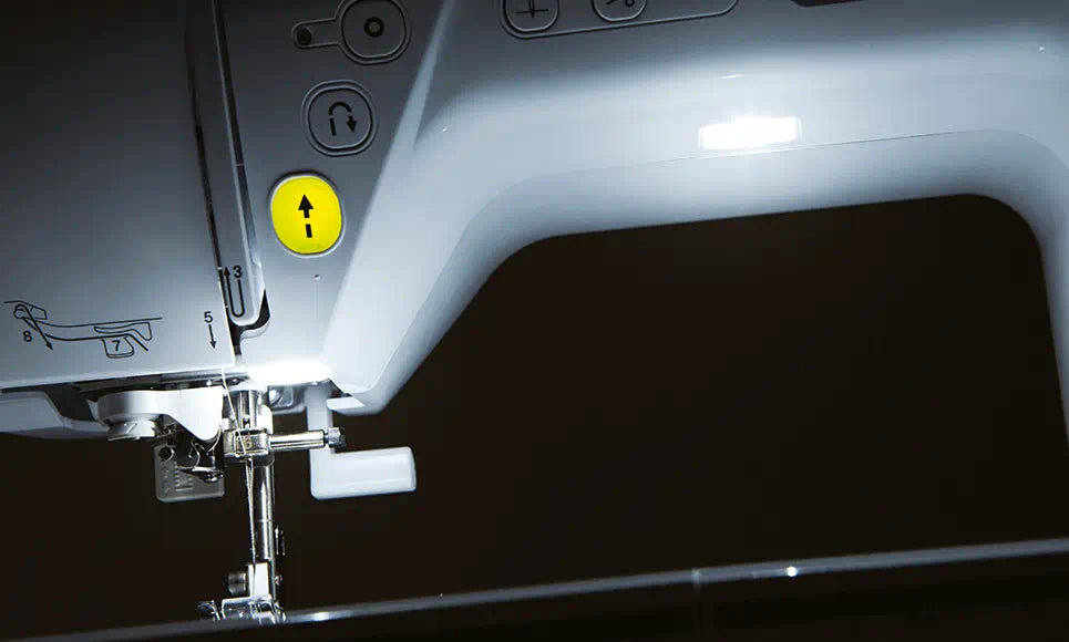 Alt description: "Illuminated sewing area of the Brother Innov-is NV1800Q with LED lighting, showing the needle threading guide and convenient needle control buttons.