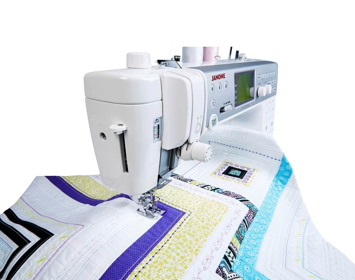 Janome Memory Craft 6700P sewing and quilting machine in action, with colourful quilt fabric under the needle, showcasing the sleek design and advanced stitching capabilities.