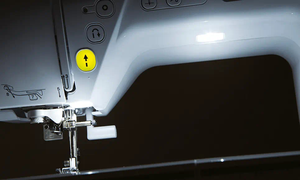 Alt description: "Illuminated sewing area of the Brother Innov-is NV1800Q with LED lighting, showing the needle threading guide and convenient needle control  buttons.